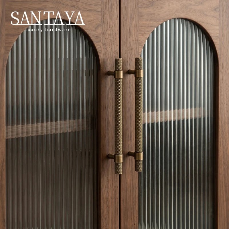 Long antique brass pulls fitted to arched glass cabinet doors