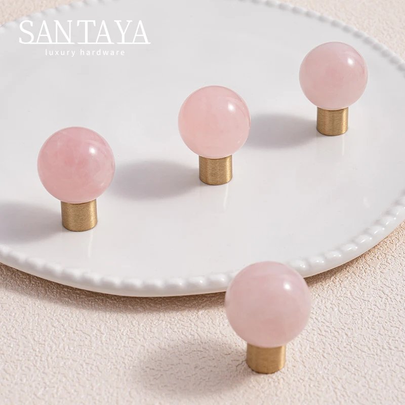 Pink spherical cabinet knobs with gold coloured brass bases