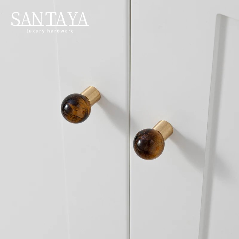 Pair of brown stone drawer knobs fitted to white cupboard doors