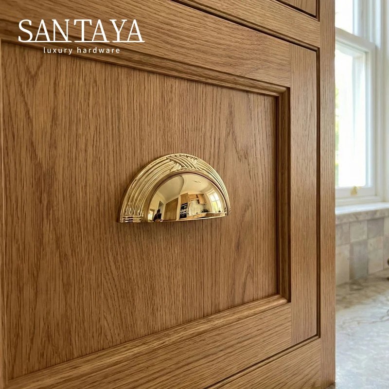 Shell shaped brass handle installed on a wooden cupboard door