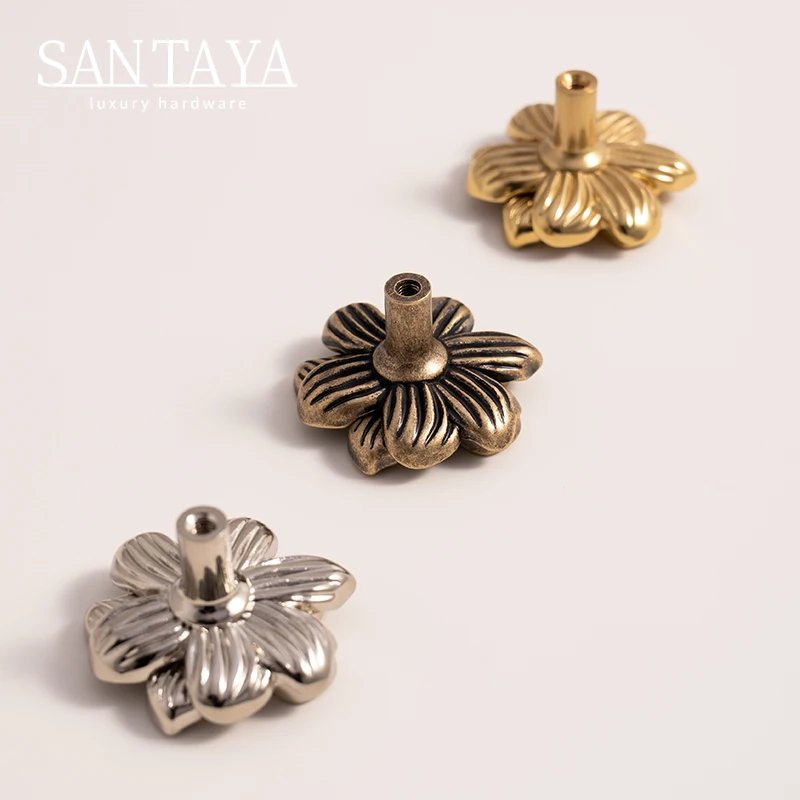 Three floral brass furniture knobs showing petal relief and base profiles