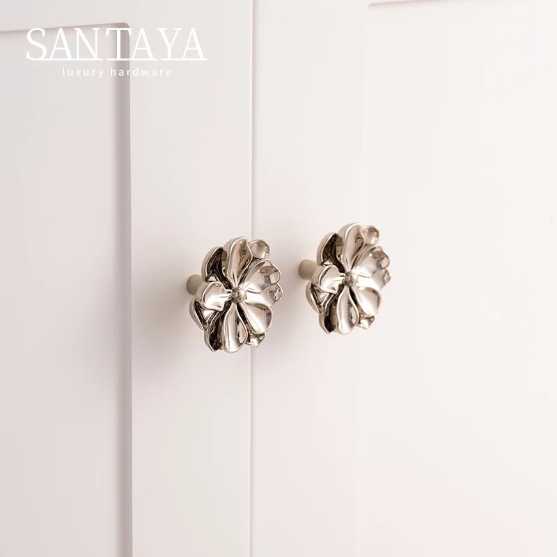 Silver coloured camellia knobs fitted to white cabinet doors
