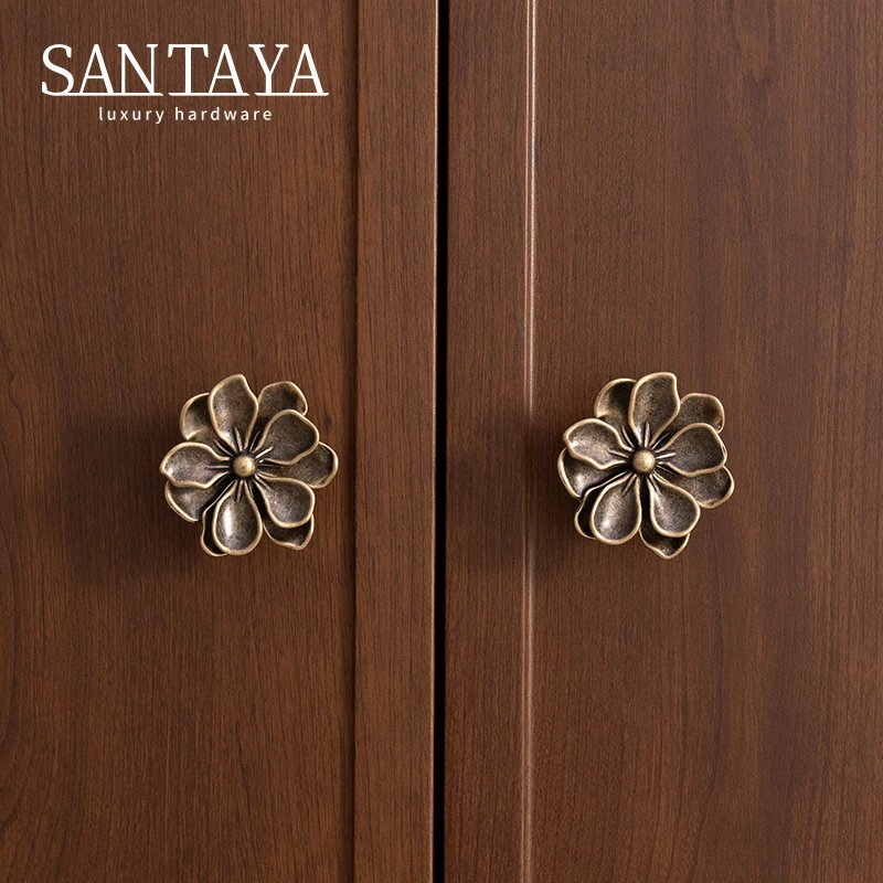Antique brass flower knobs fitted to dark wooden cupboard doors