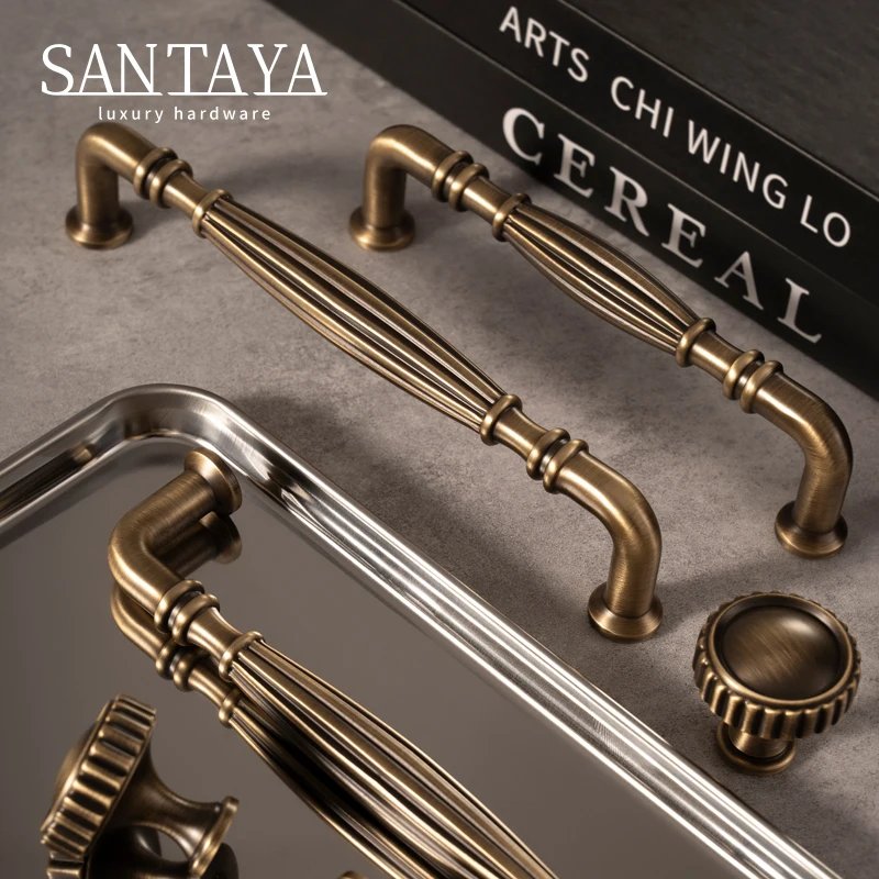 Antique brass cabinet bar handles and round knobs arranged beside a book