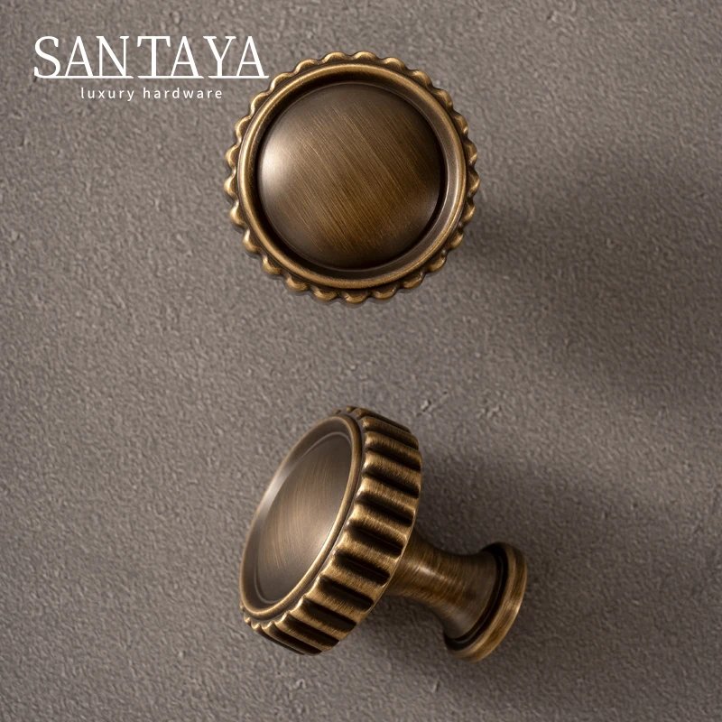 Round antique brass furniture knob showing its ridged edge and mounting stem