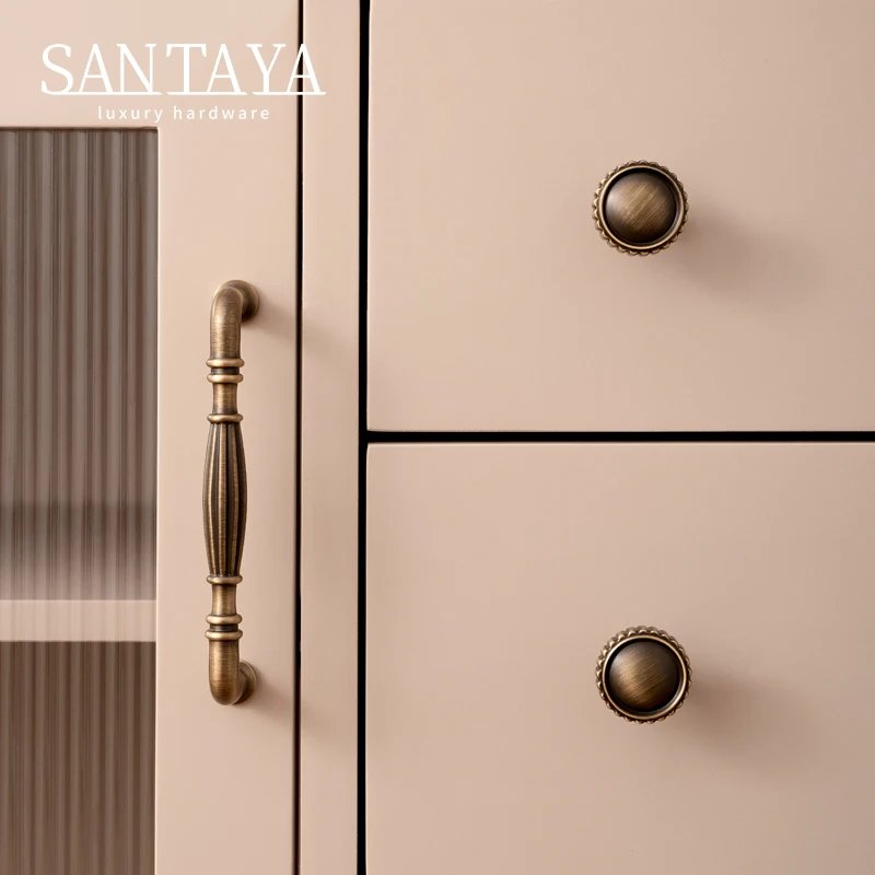 Antique brass bar handle and round knobs fitted to beige furniture